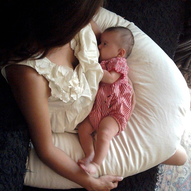 Mère allaitant son bébé sur un coussin d'allaitement confortable.