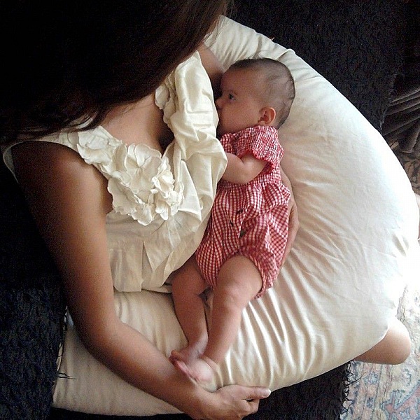Mère allaitant son bébé sur un coussin d'allaitement confortable.
