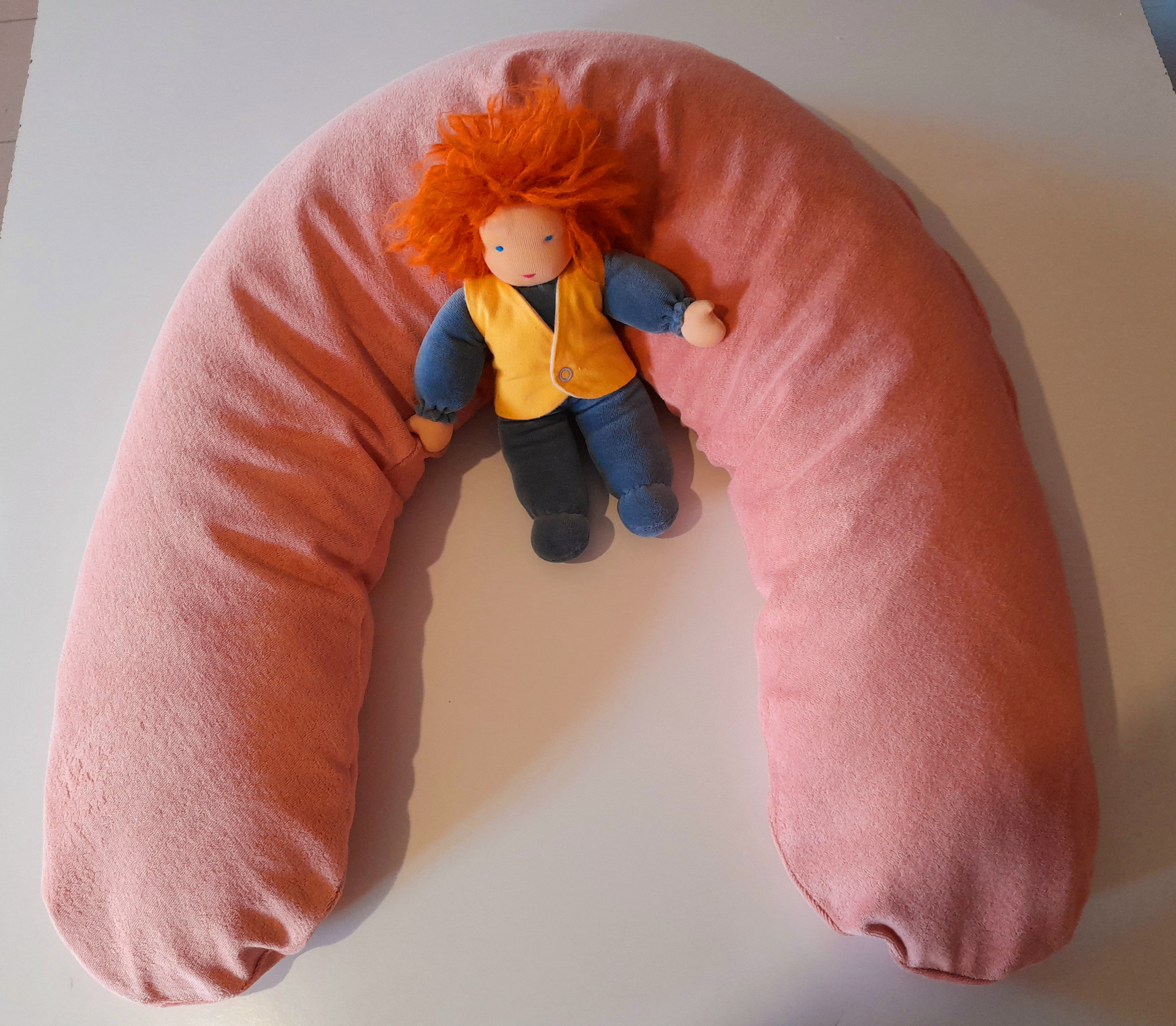 Coussin d'allaitement rose avec une poupée en tissu.